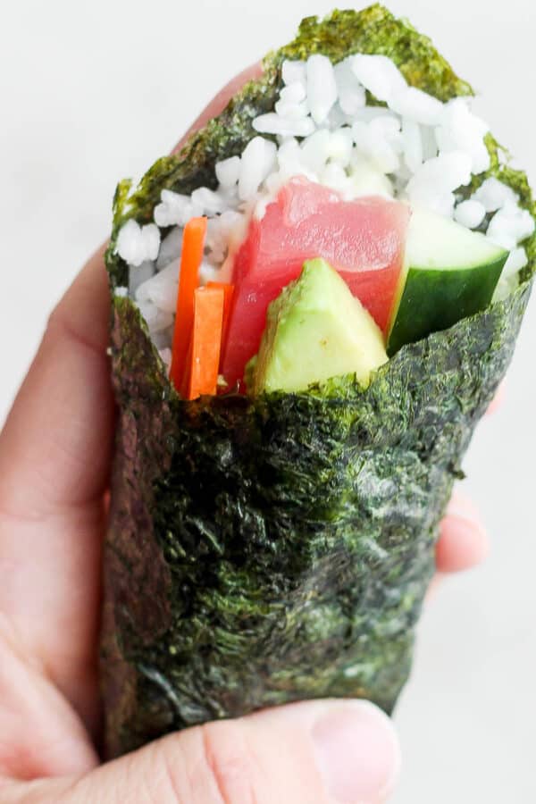 Someone holding a sushi hand roll.