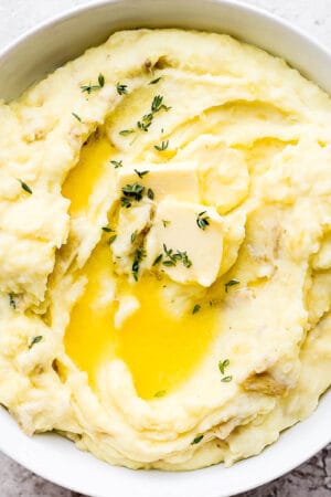Bowl of yukon gold mashed potatoes with herbs and butter.