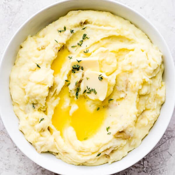 Bowl of yukon gold mashed potatoes with herbs and butter.