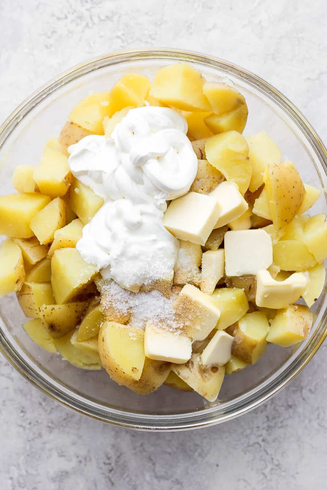 Boiled potatoes in a bowl with the rest of the ingredients added.