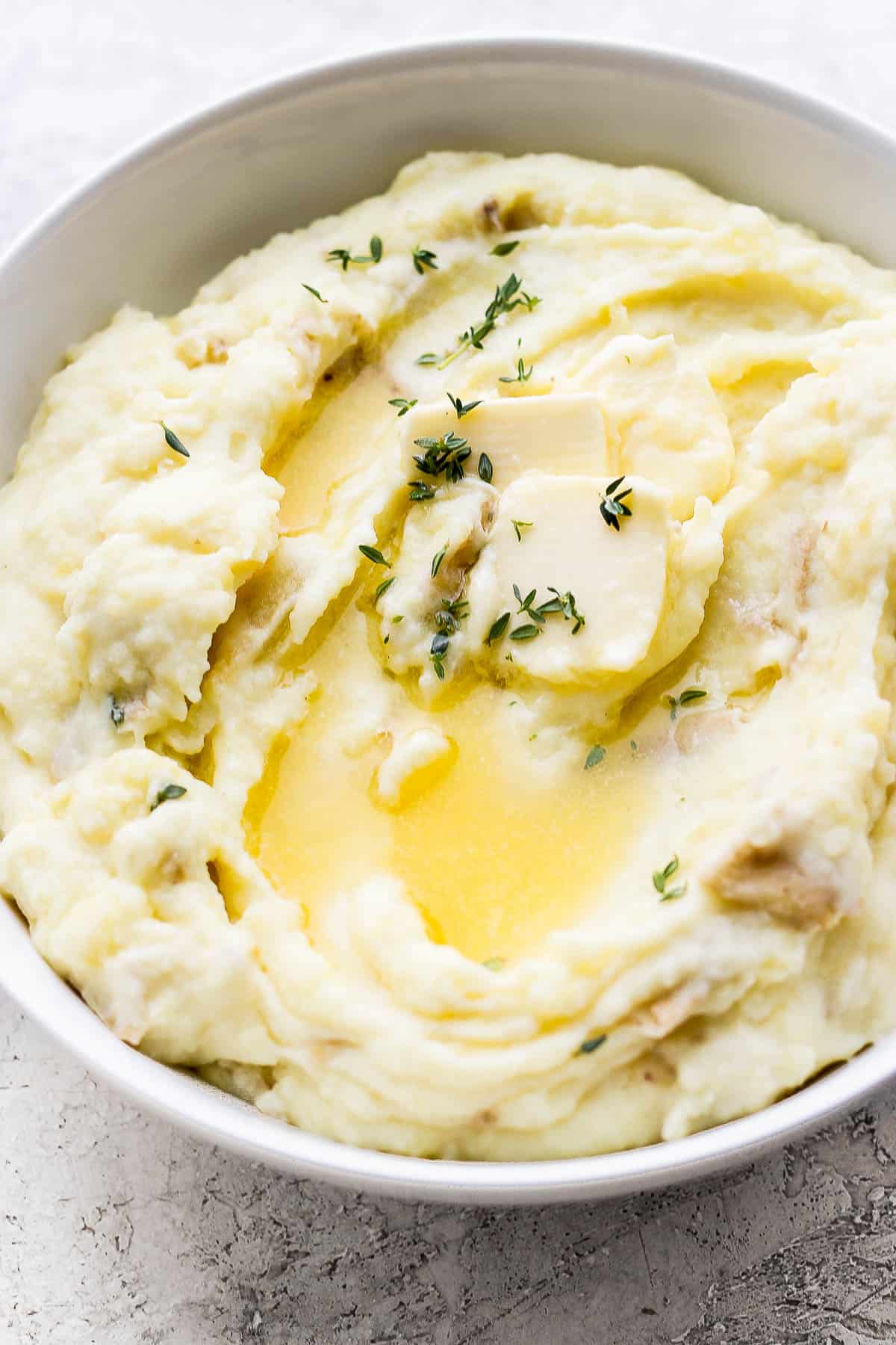 Mashed potatoes with a pad of butter and fresh thyme.