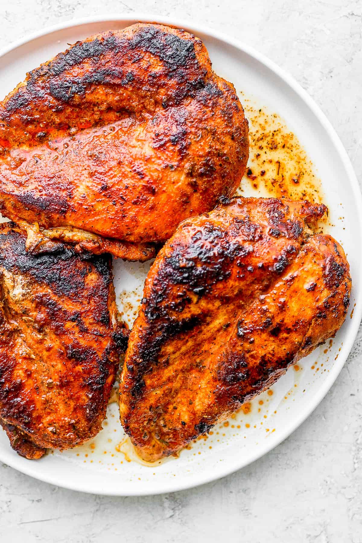Blackened chicken breasts on a plate.