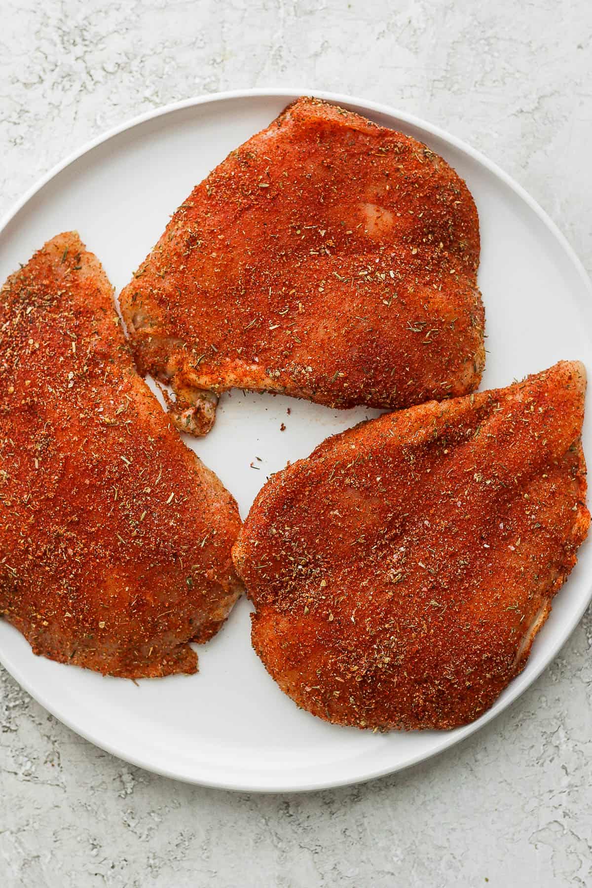 Chicken breasts seasoned with blackened seasoning on a plate.