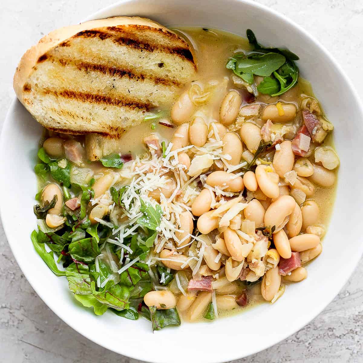 Bowl of brothy beans with grilled bread.