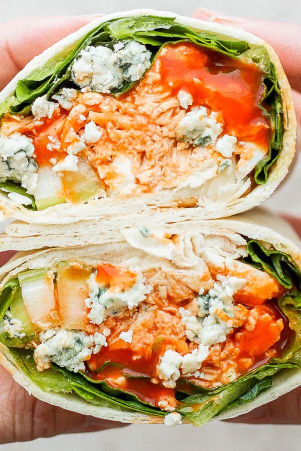 Someone holding two sides of a buffalo chicken wrap, showing the inside.