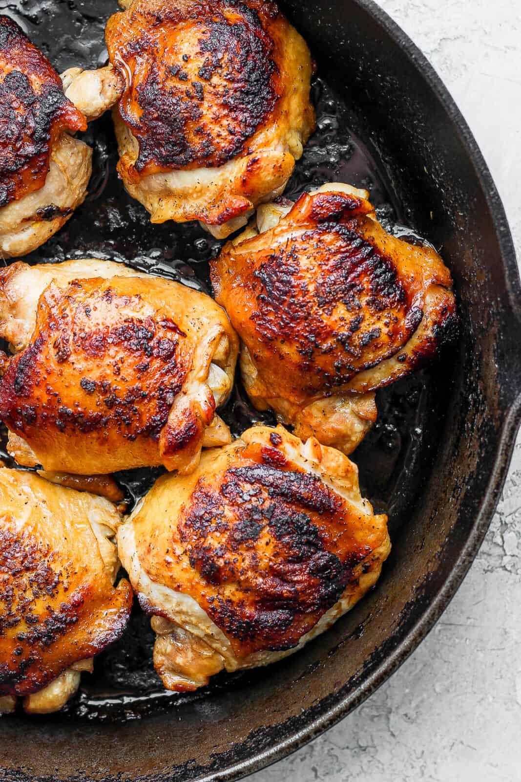 Seared chicken thighs in a cast iron skillet.