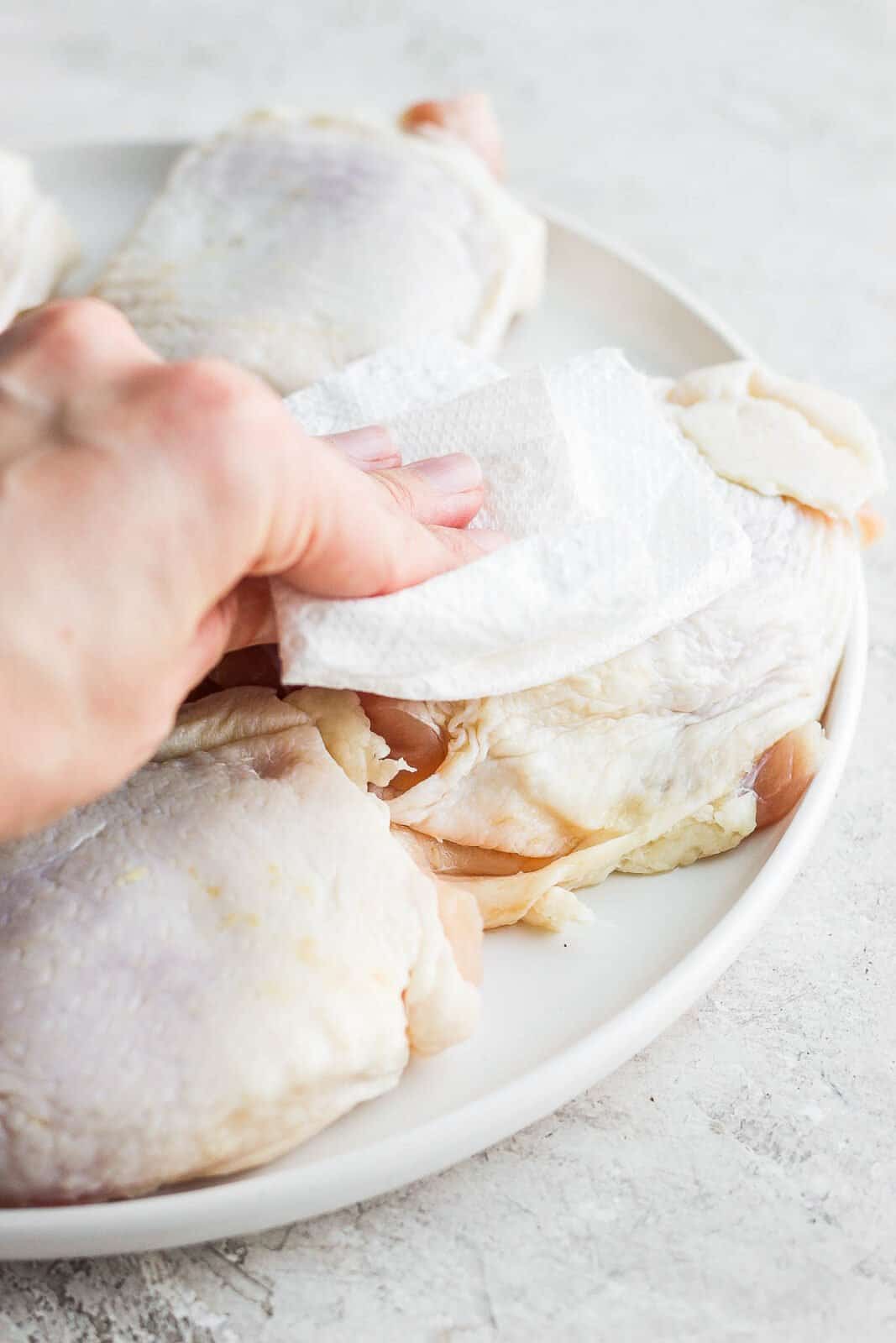 Patting chicken dry with a paper towel.