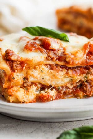 A large slice of homemade lasagna on a plate.