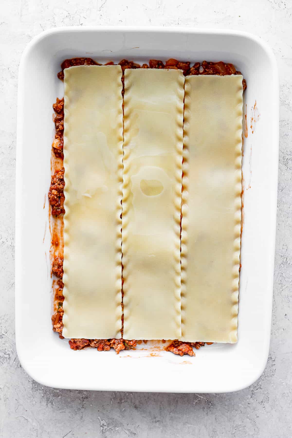 Noodles added on top of the meat sauce.