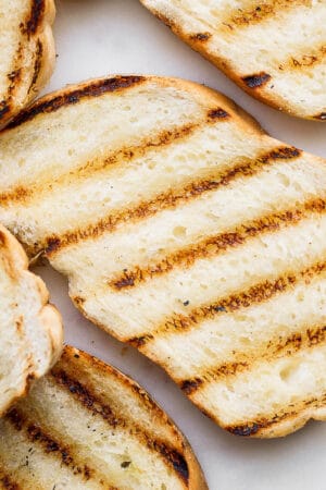 Several pieces of grilled bread on a piece of marble.