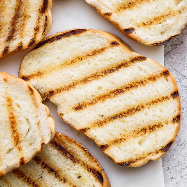 Several pieces of grilled bread on a piece of marble.