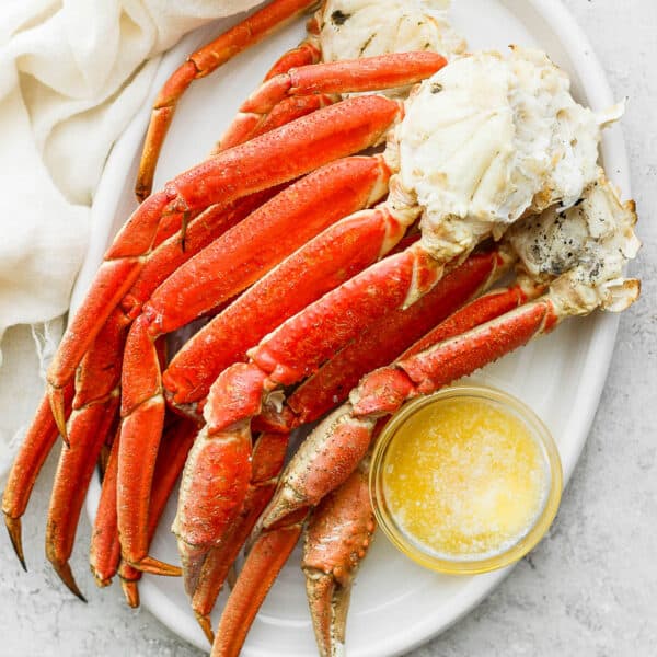 Grilled crab legs on a platter with little bowl of melted butter.