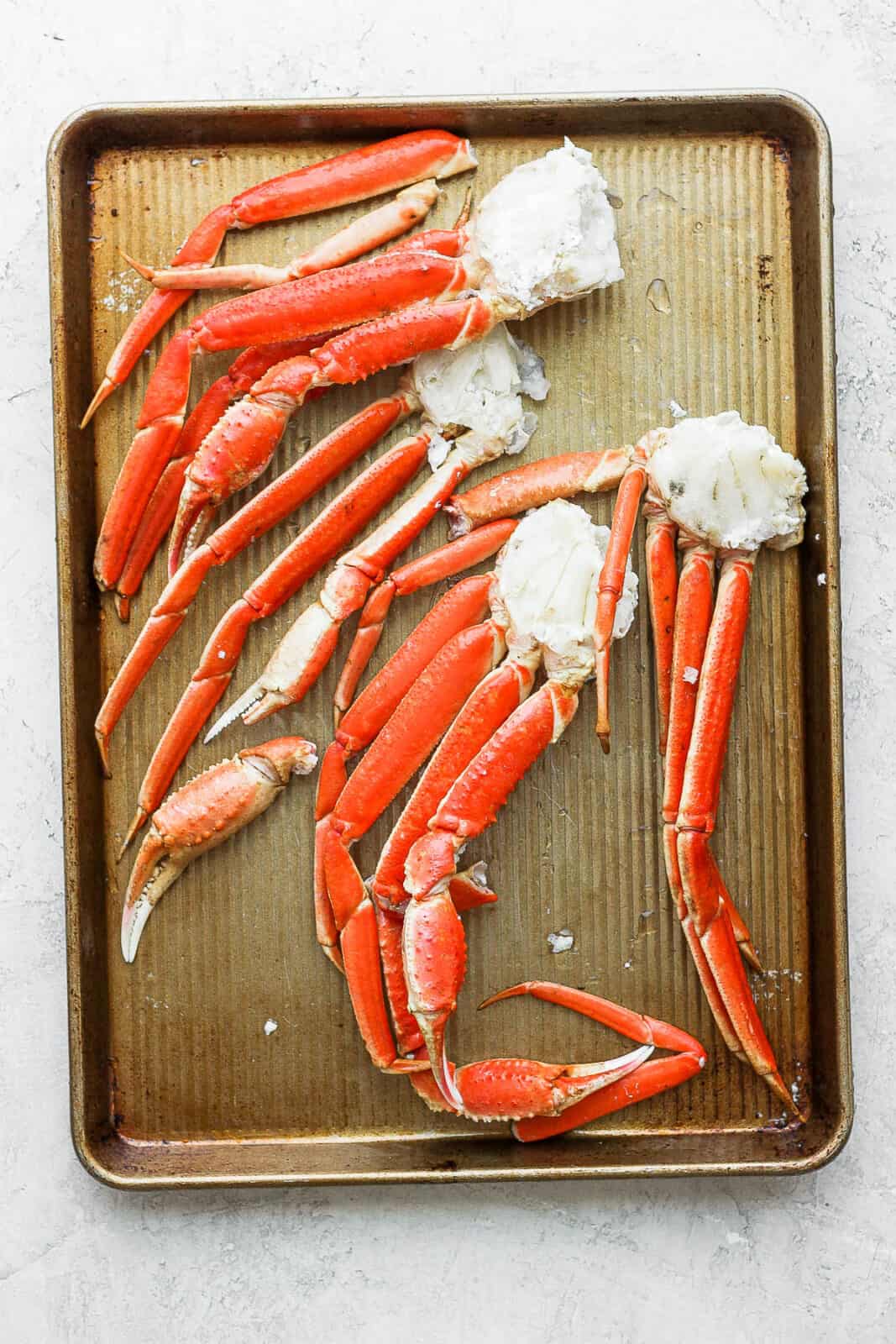 Crab legs thawing on a sheet pan.