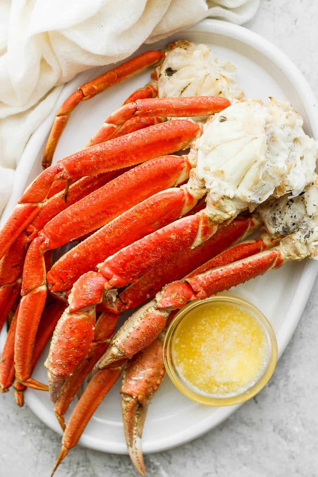 Grilled crab legs on a plate with melted butter.