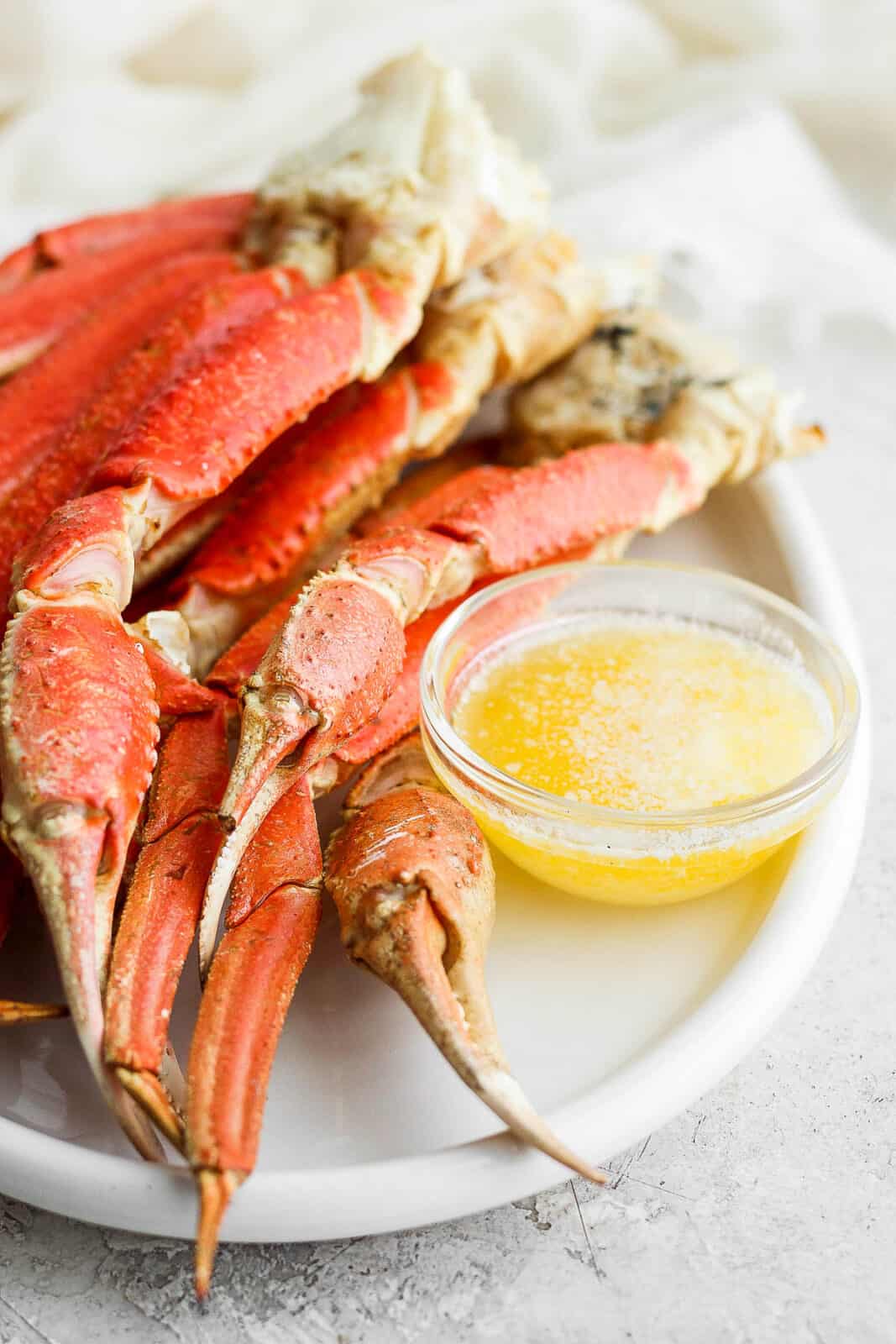 Grilled crab legs on a plate with melted butter.