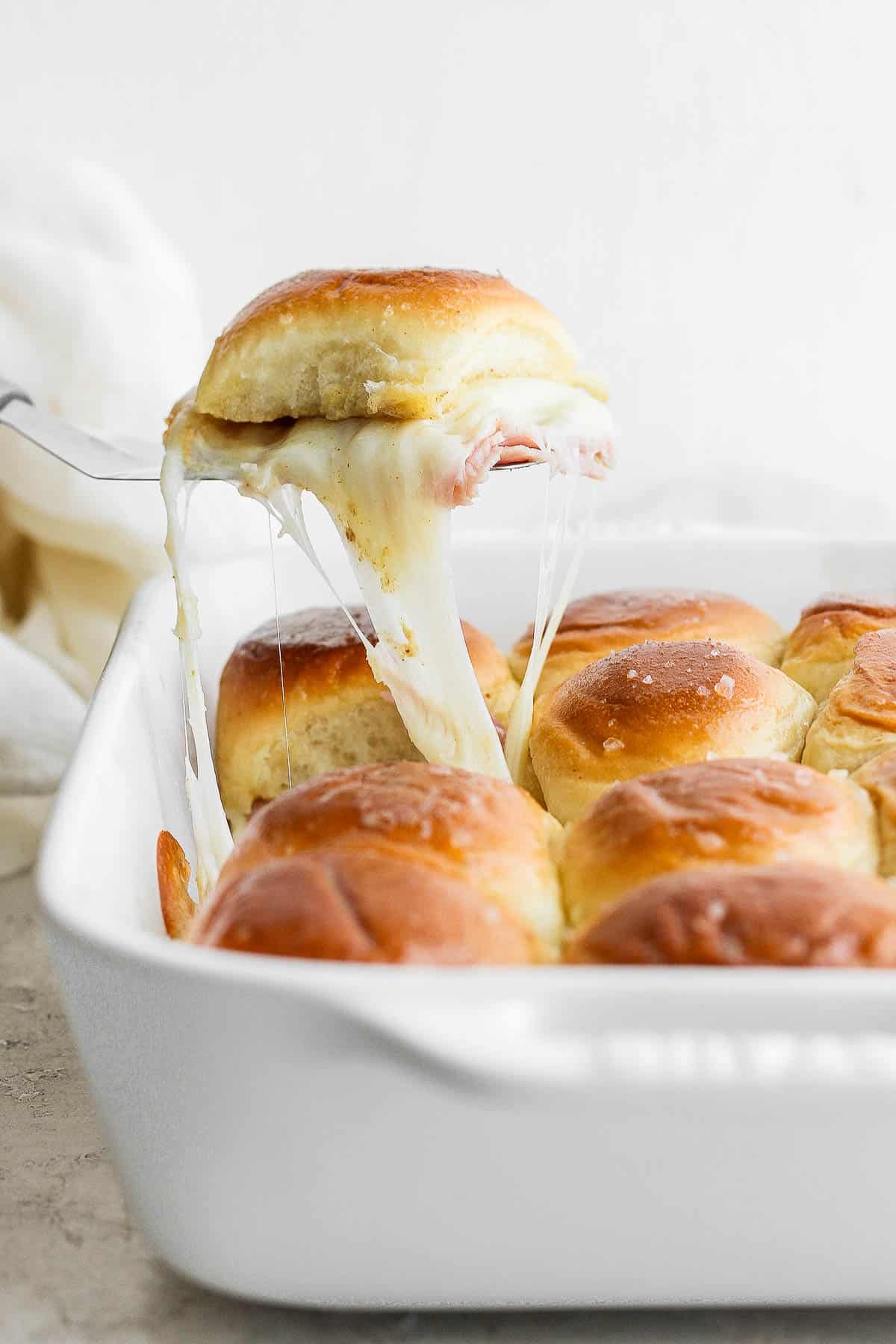 A spatula pulling a slider out of the dish.