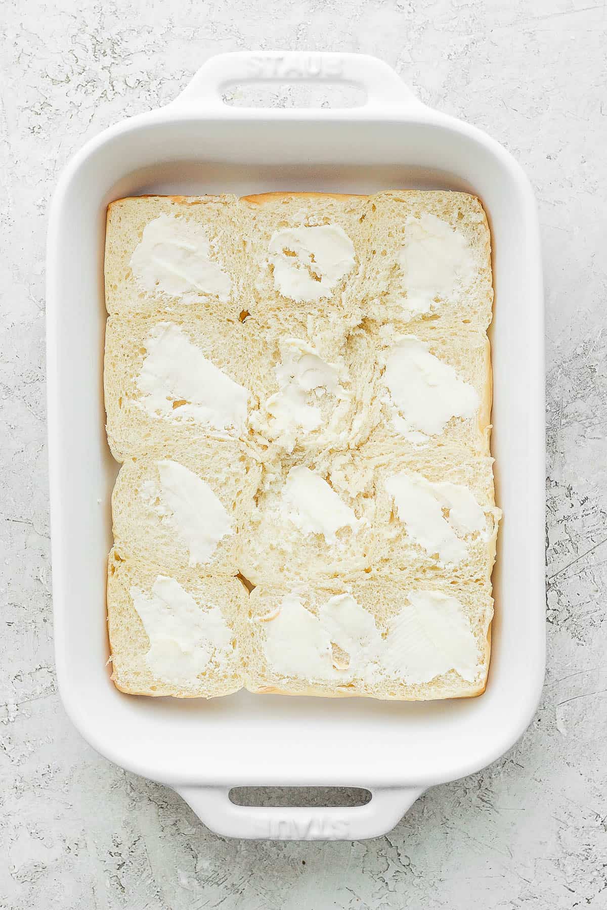 The bottoms of the dinner rolls in a dish with butter spread on.