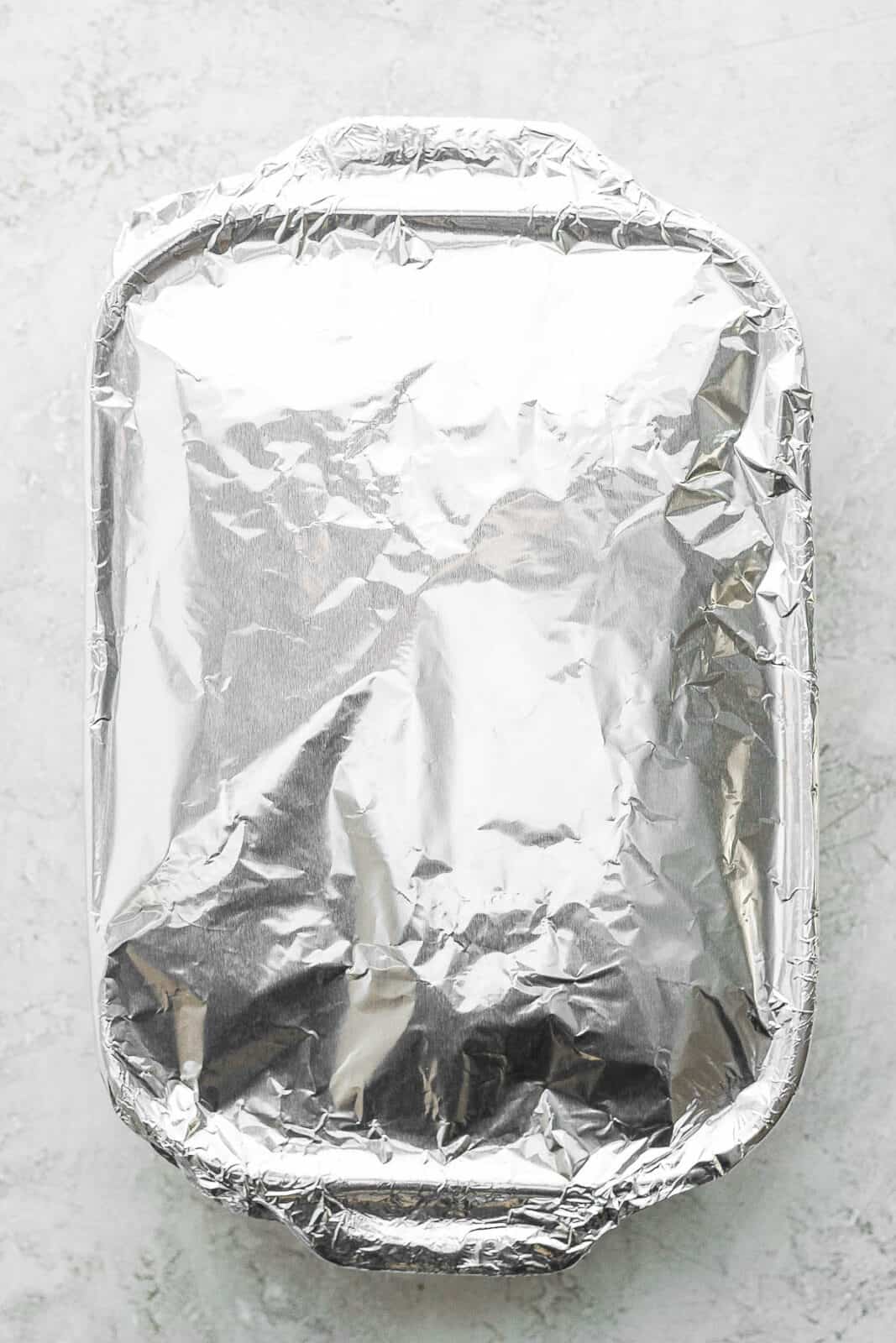 The pan of sliders with aluminum foil on top.