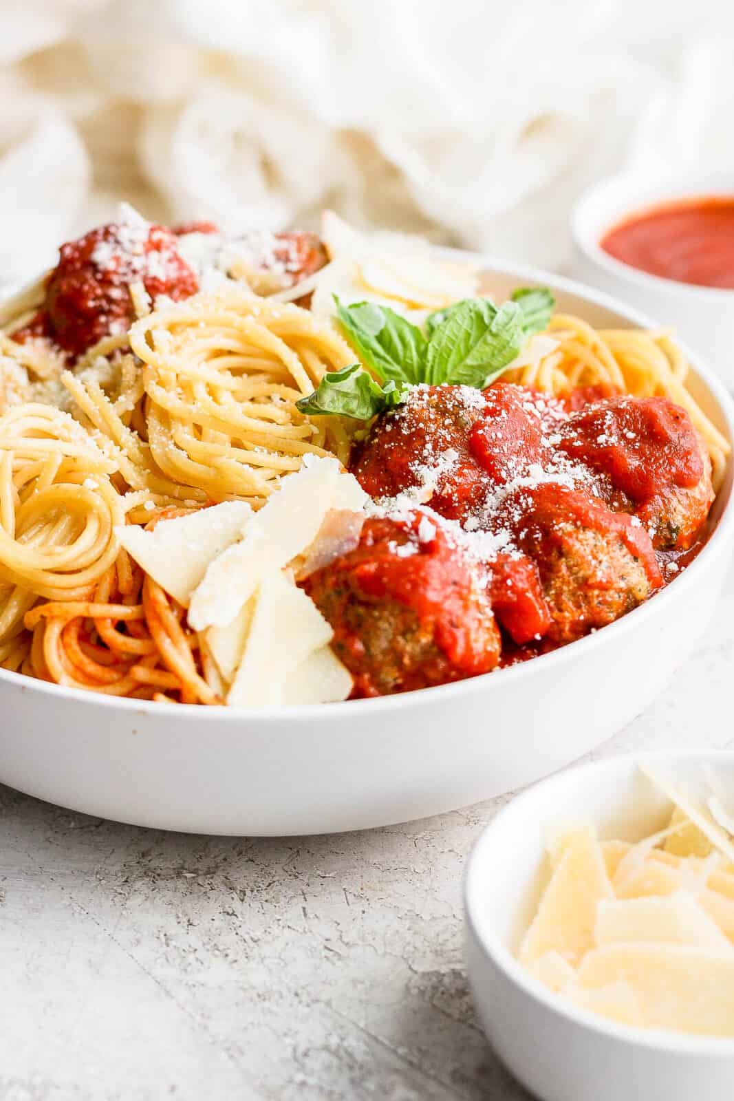 Side view of a bowl of pesto meatballs and spaghetti.