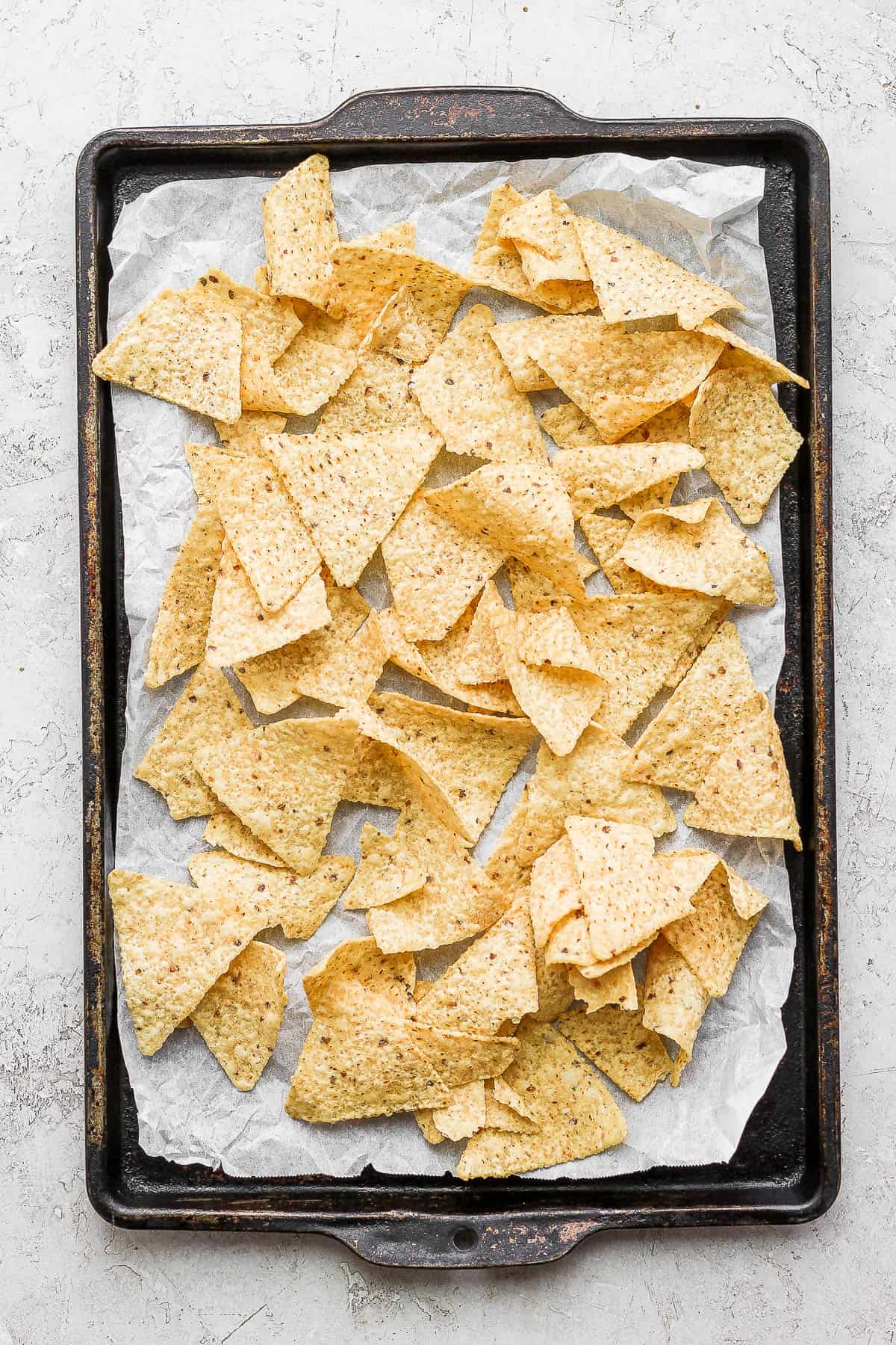 Tortilla chips on a parchment-lined baking sheet.