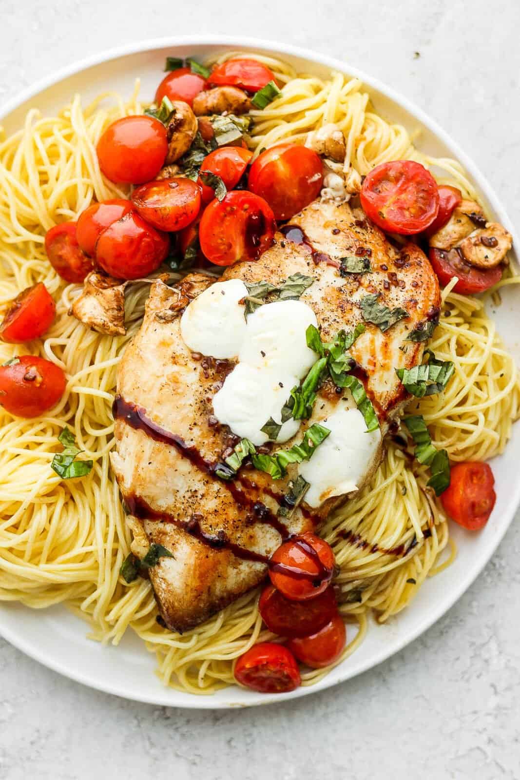 Plate of angel hair pasta with balsamic chicken on top. 