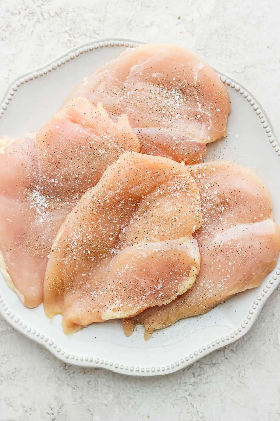 Four chicken breasts seasoned with salt and pepper. 