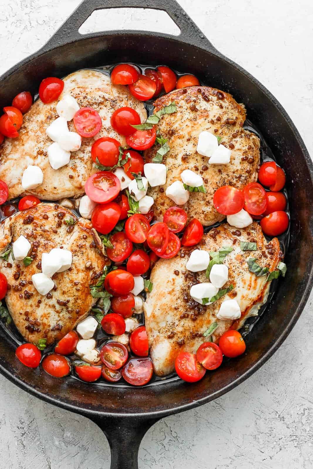 Cast iron skillet with seared chicken breasts, balsamic reduction, tomatoes, basil and mozzarella. 