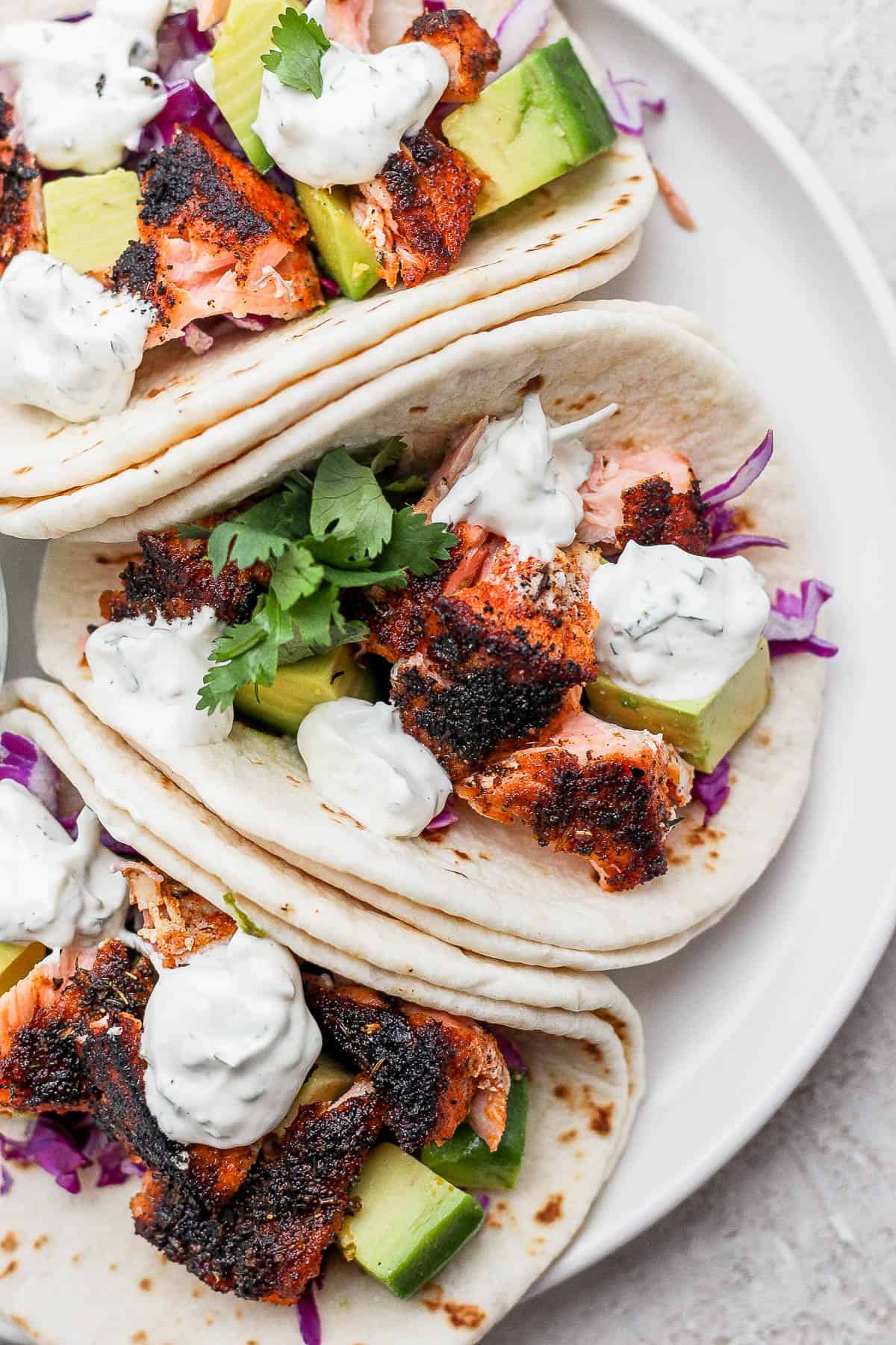 Three blackened salmon tacos on a plate.