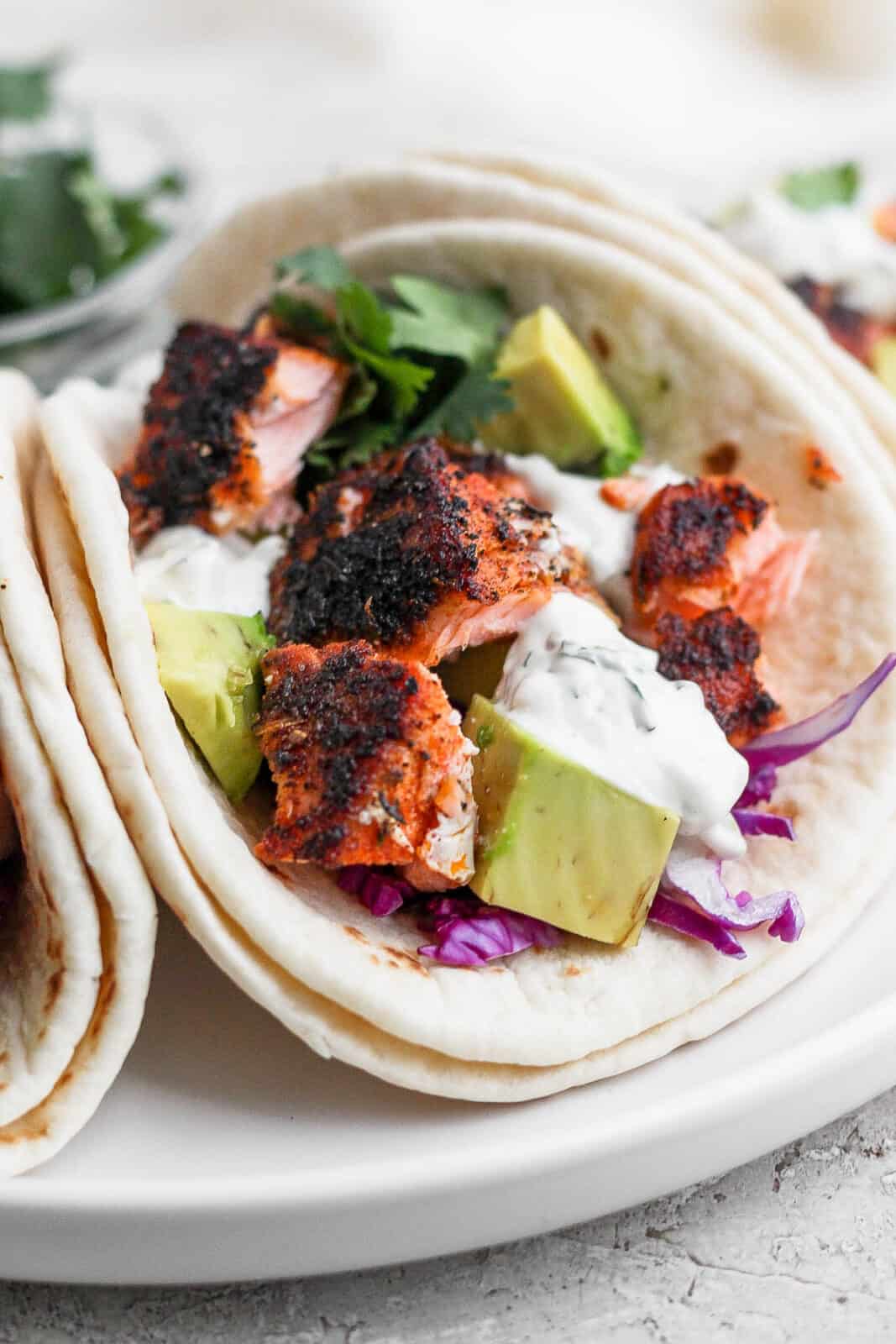 A close-up view of a blackened salmon taco with cilantro lime crema.