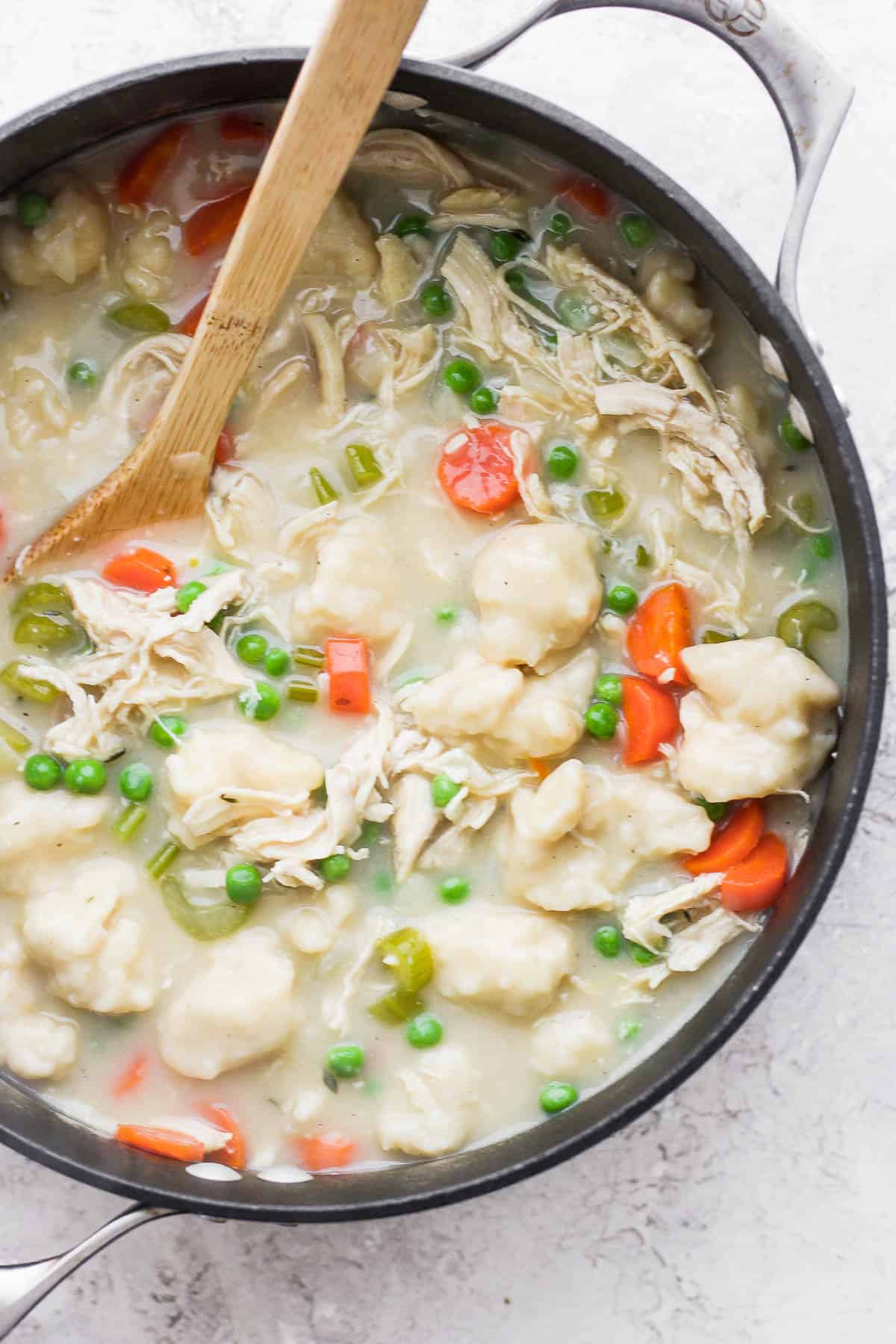 Chicken and dumpling soup in a crockpot with a wooden spoon.