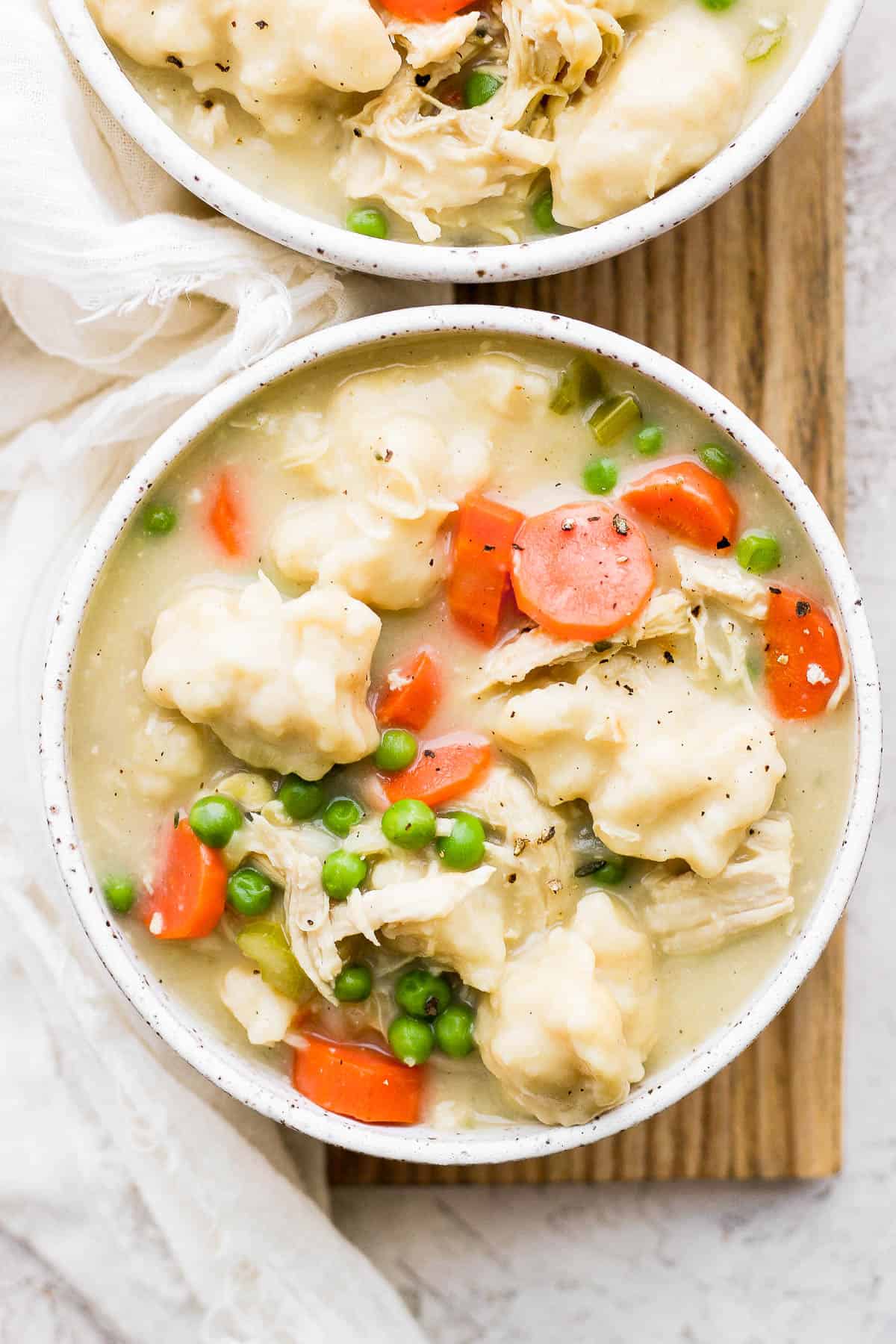 Bowls of chicken and dumpling soup on a wooden board.