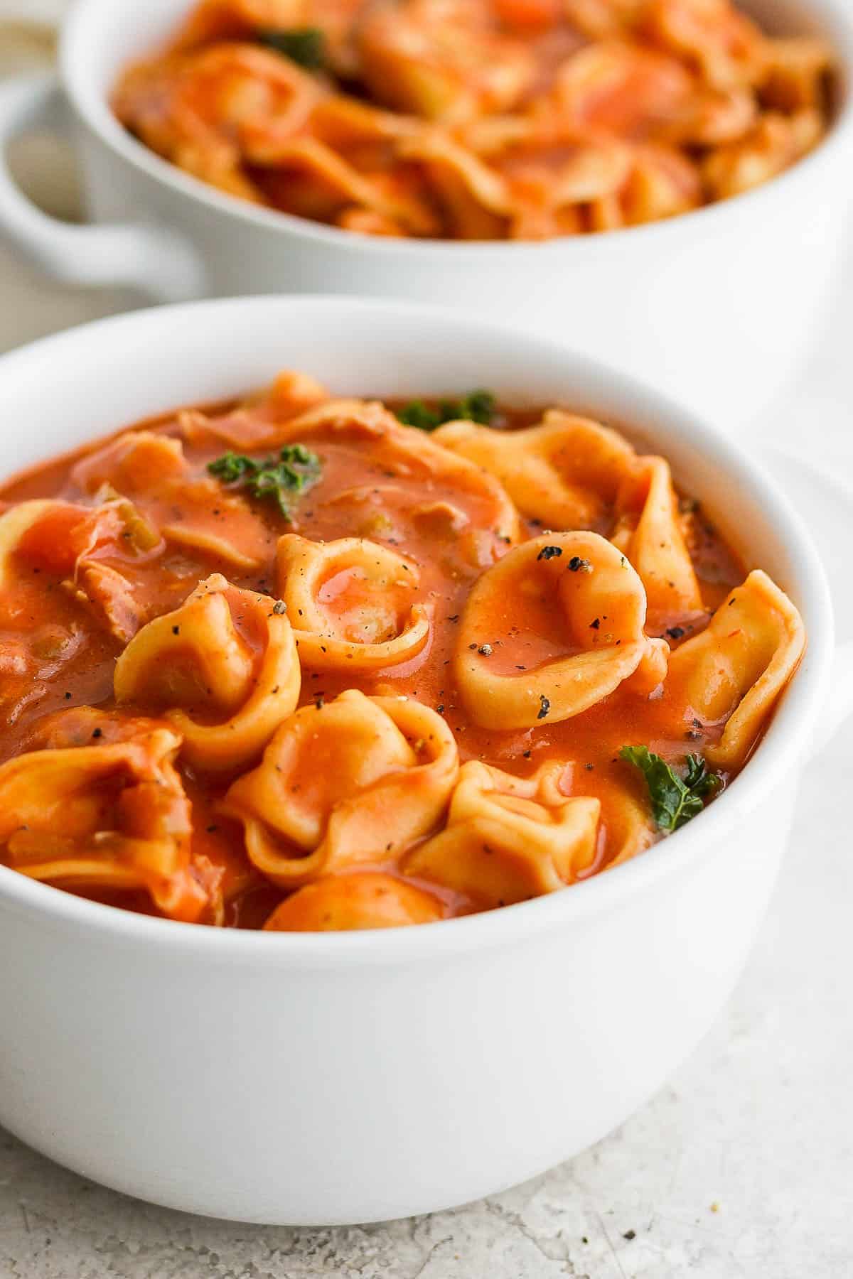 Two bowls of easy chicken tortellini soup with kale.