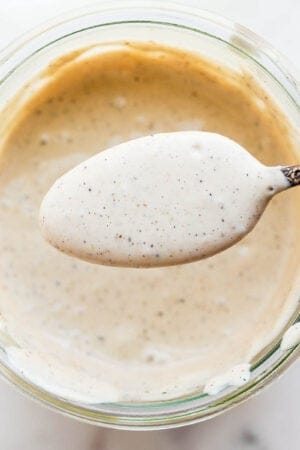 A jar of dairy free caesar dressing with spoonful over top.