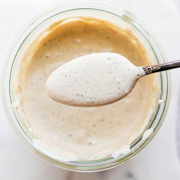 A jar of dairy free caesar dressing with spoonful over top.