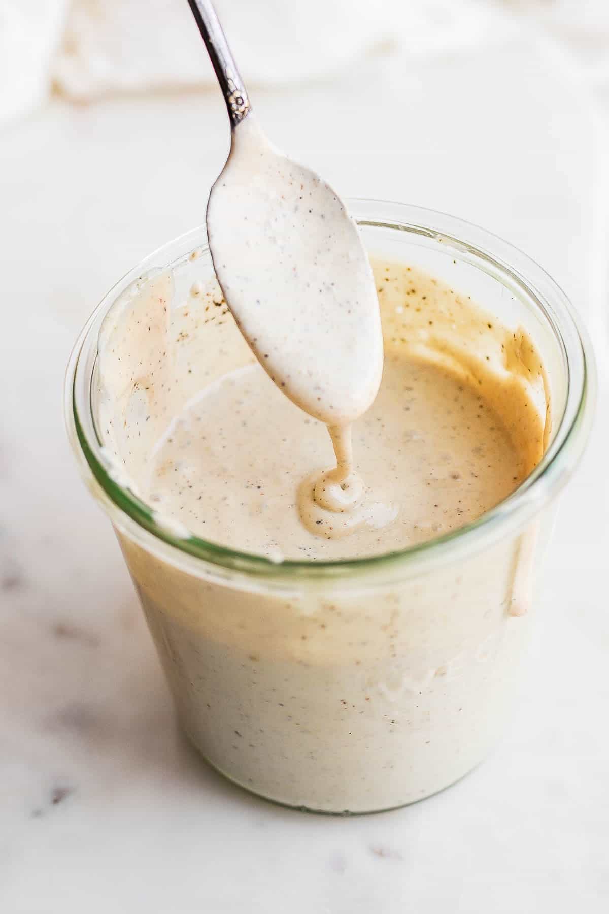 Whole30 dairy free caesar dressing in a jar with a spoon.