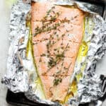 Foil baked salmon on a baking sheet with fresh thyme.