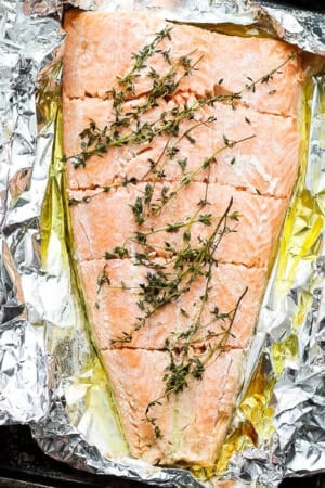 Foil baked salmon on a baking sheet with fresh thyme.