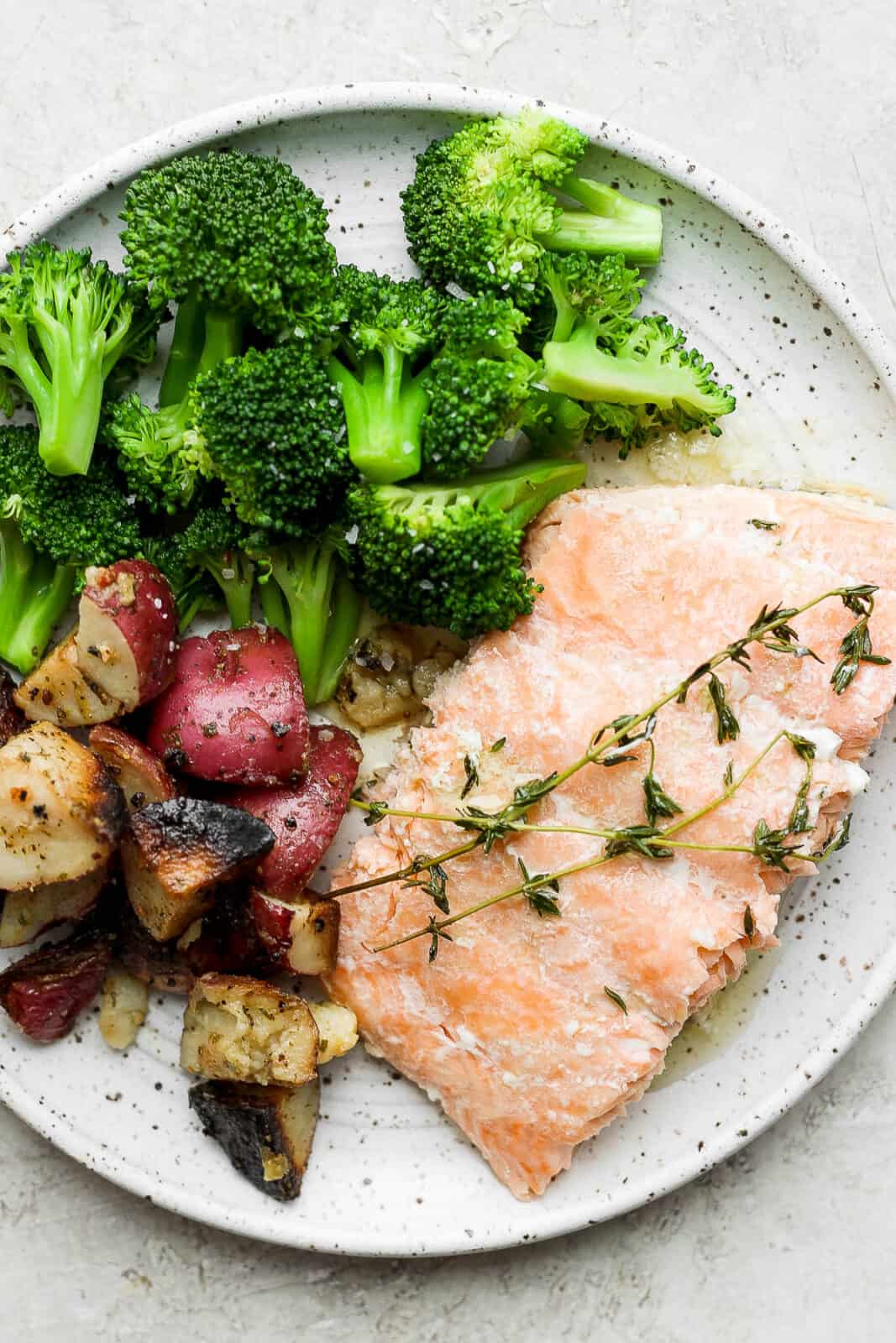 Baked salmon on a plate with potatoes and broccoli.