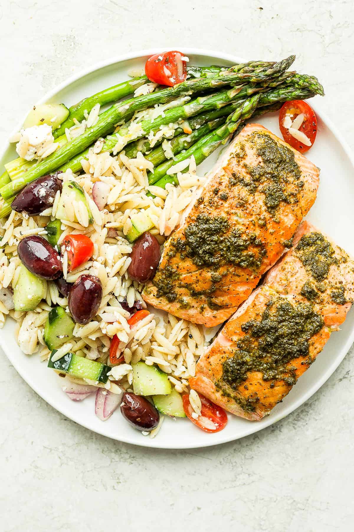 Plate of pesto salmon, asparagus and greek orzo salad. 