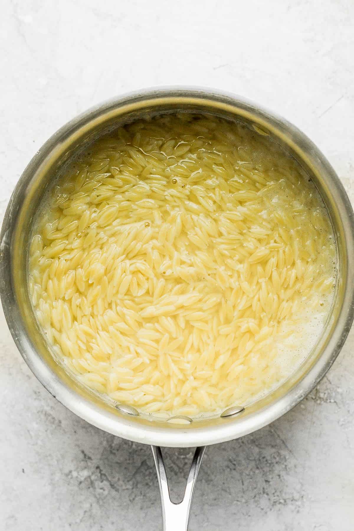 Orzo cooked but still in a water in a saucepan before draining. 