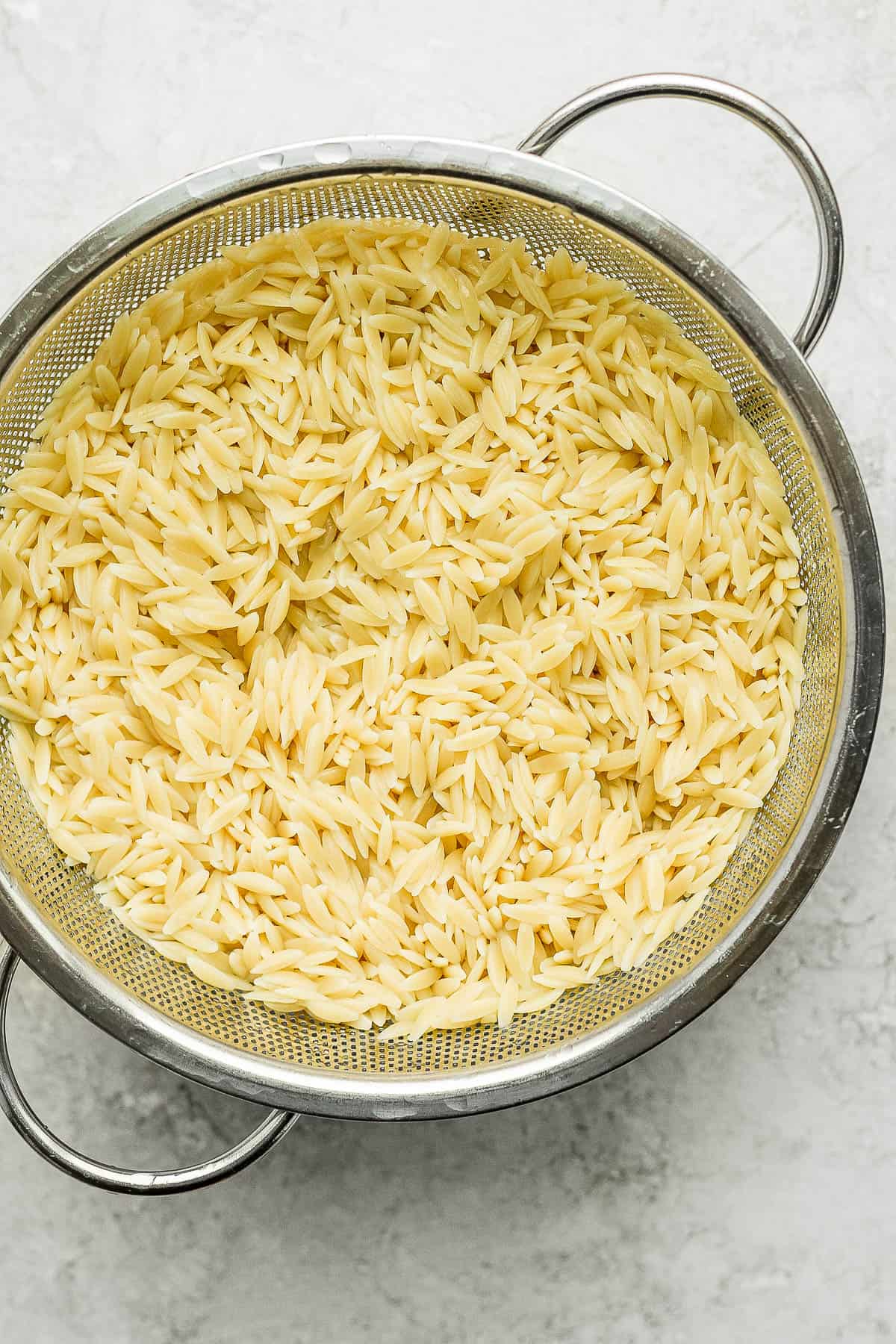 Cooked orzo that has been drained in a colander.