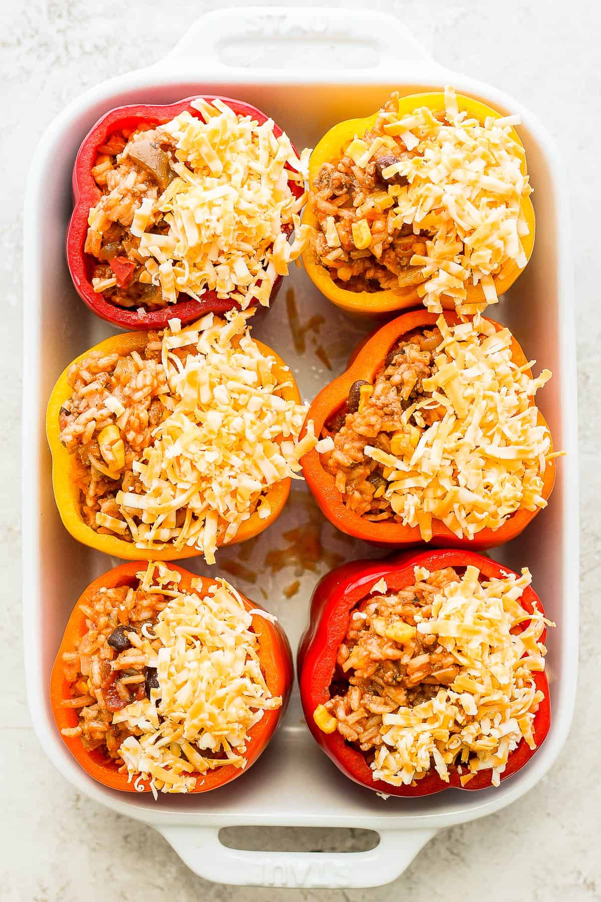 Same stuffed bell peppers in a pan topped with cheese.