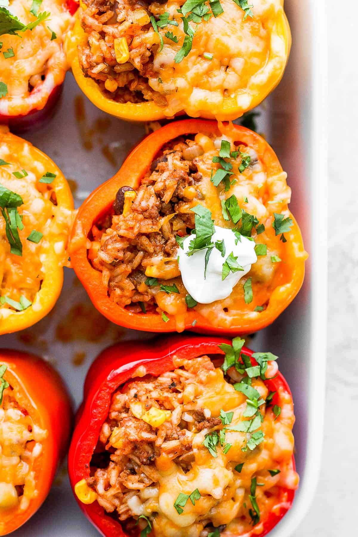 Close up of mexican stuffed peppers out of the oven with melted cheese and sour cream.