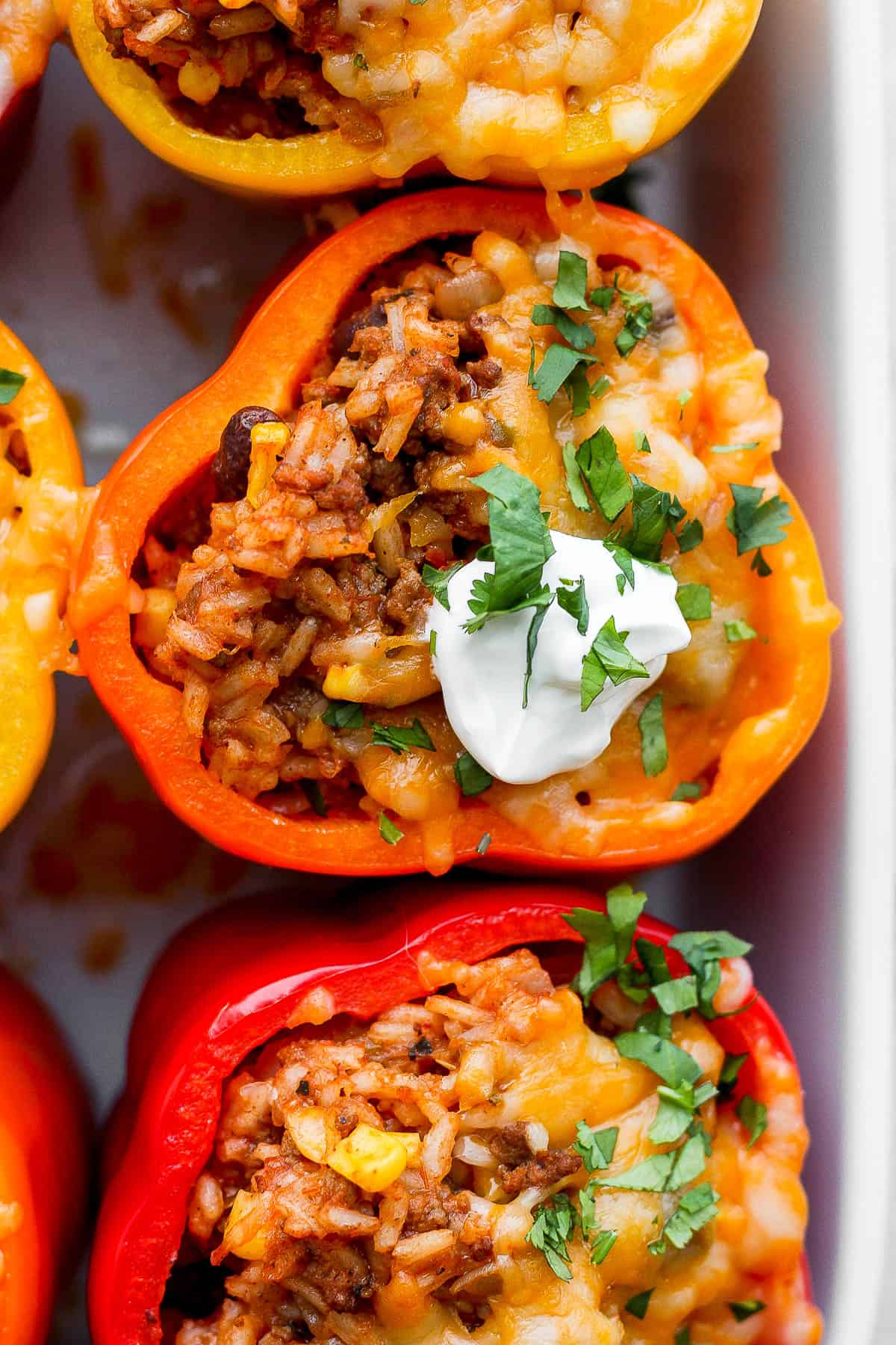 Close up of a mexican stuffed pepper with sour cream and chopped cilantro.