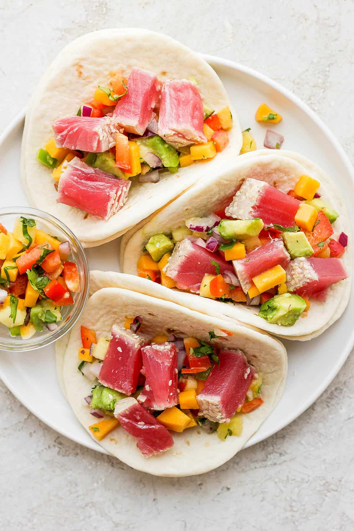 Quick and easy ahi tuna tacos on a plate with a side of mango pineapple salsa.