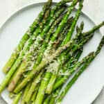 A plate of asparagus that was cooked in the air fryer, topped with parmesan cheese.