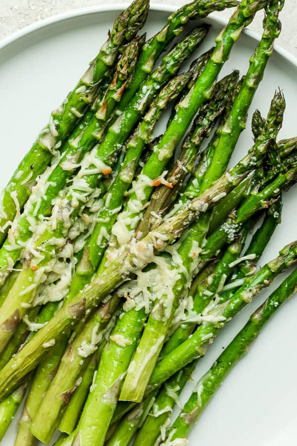 A plate of asparagus that was cooked in the air fryer, topped with parmesan cheese.