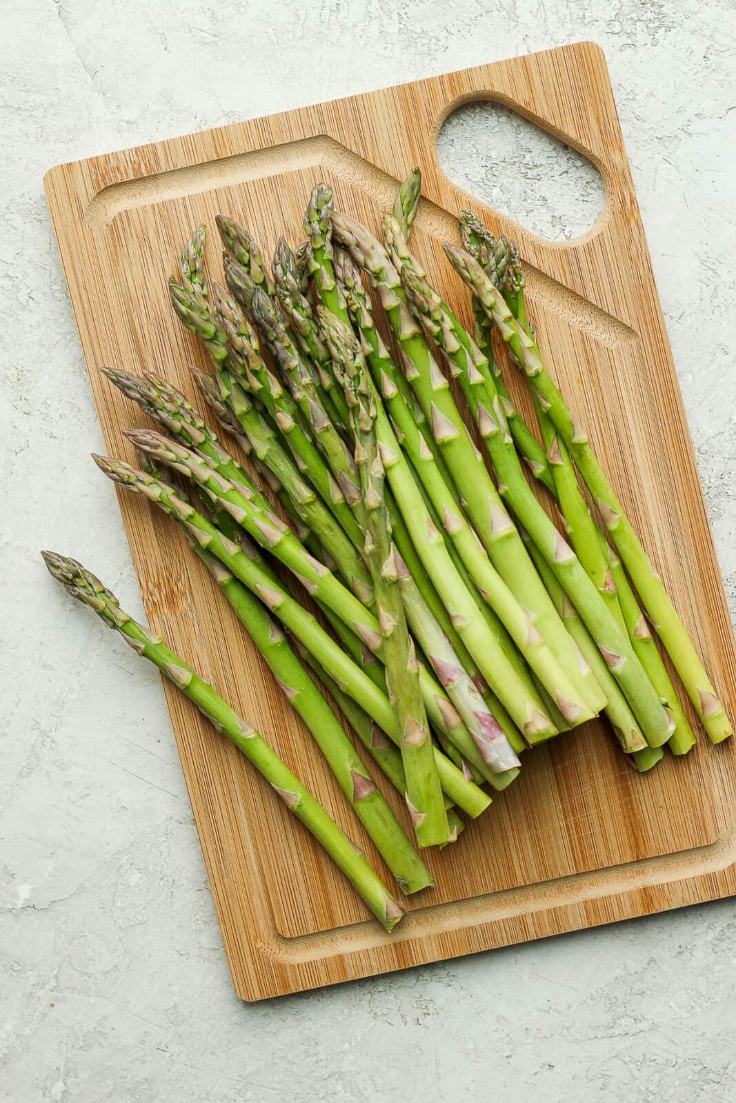 Trimmed asparagus on a wood cutting board.