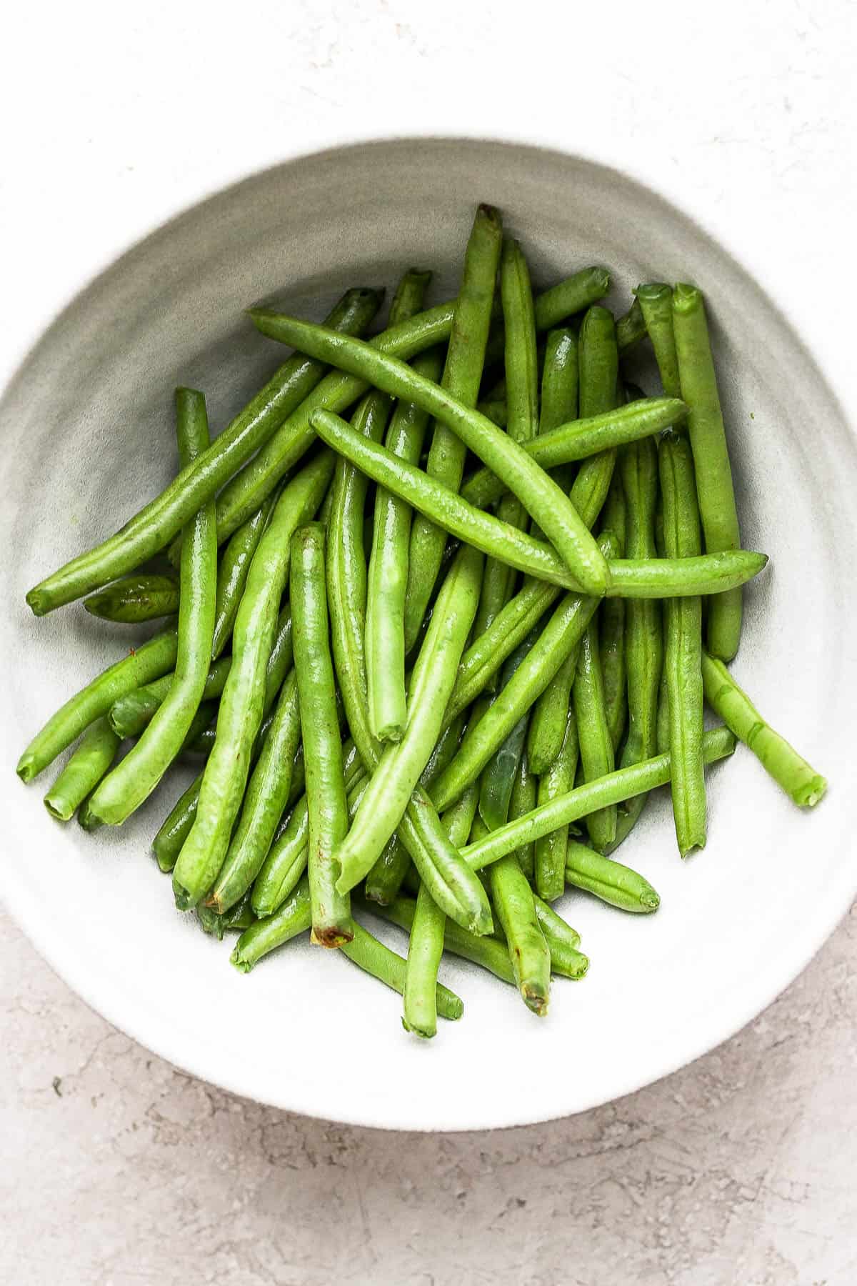 Plain green beans in a white bowl.