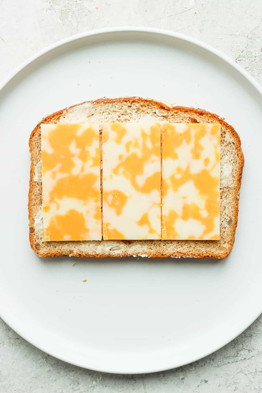 Slices of cheese on a buttered piece of bread.